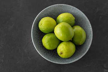Image showing close up of whole limes in bowl on slate table top