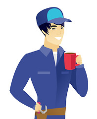 Image showing Young asian mechanic holding cup of coffee.