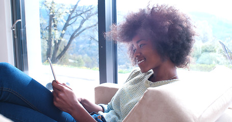 Image showing black woman sitting on sofa and using mobile phone