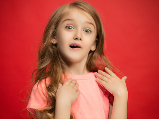 Image showing The happy teen girl standing and smiling against red background.