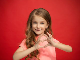 Image showing The happy teen girl standing and smiling against red background.