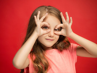 Image showing The happy teen girl standing and smiling against red background.