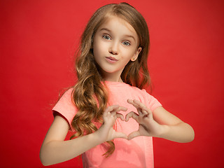 Image showing The happy teen girl standing and smiling against red background.