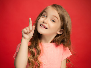 Image showing The happy teen girl standing and smiling against red background.