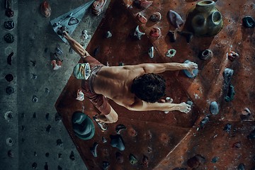 Image showing Free climber young man climbing artificial boulder indoors