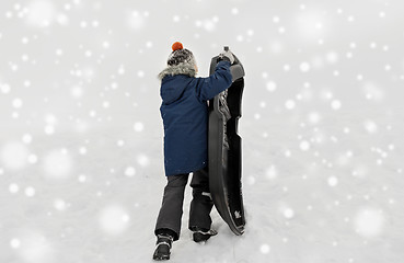 Image showing little boy with sled climbing snow hill in winter