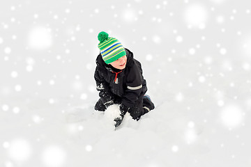 Image showing happy little boy playing with snow in winter