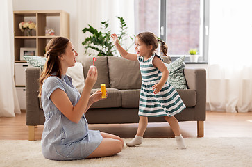 Image showing pregnant mother and daughter blowing soap bubbles