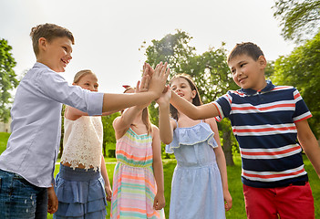 Image showing group of happy kids making high five outdoors