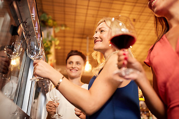 Image showing happy women pouring wine from dispenser at bar