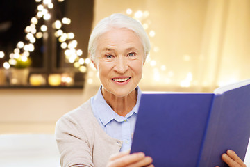 Image showing smiling senior woman reading book on christmas