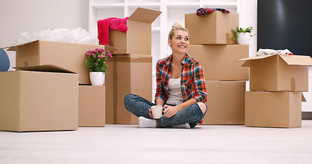 Image showing woman with many cardboard boxes sitting on floor