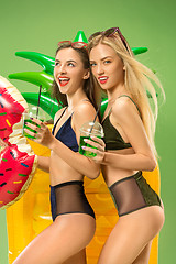 Image showing Cute girls in swimsuits posing at studio. Summer portrait caucasian teenagers on green background.