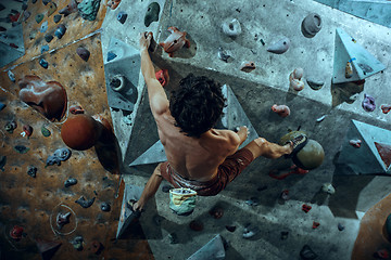 Image showing Free climber young man climbing artificial boulder indoors