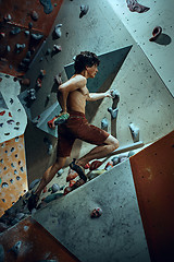 Image showing Free climber young man climbing artificial boulder indoors