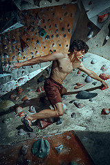 Image showing Free climber young man climbing artificial boulder indoors