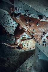 Image showing Free climber young man climbing artificial boulder indoors