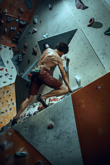 Image showing Free climber young man climbing artificial boulder indoors