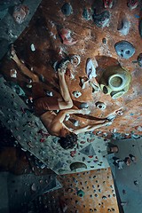 Image showing Free climber young man climbing artificial boulder indoors