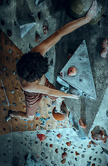 Image showing Free climber young man climbing artificial boulder indoors