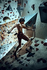 Image showing Free climber young man climbing artificial boulder indoors