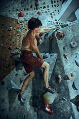 Image showing Free climber young man climbing artificial boulder indoors