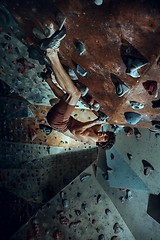 Image showing Free climber young man climbing artificial boulder indoors