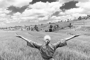 Image showing Relaxed fashionable caucasian woman wearing asian style kimono, arms rised to sky, enjoying pure nature at beautiful green rice fields on Bali island