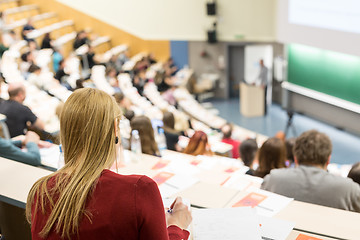 Image showing Audience in the lecture hall. Female student making notes.