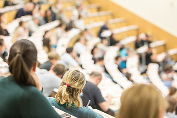 Image showing Audience in the lecture hall. Female student making notes.