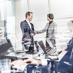 Image showing Business people shaking hands in moder corporate office.