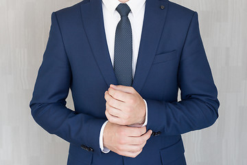 Image showing Torso of anonymous businessman wearing beautiful fashionable classic navy blue suit against grey backgound.