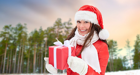 Image showing woman in santa hat with chrismas gift outdoor