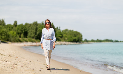 Image showing happy smiling woman walking along summer beach