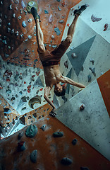 Image showing Free climber young man climbing artificial boulder indoors