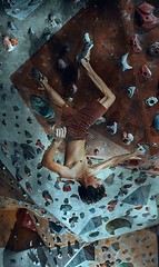 Image showing Free climber young man climbing artificial boulder indoors