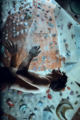 Image showing Free climber young man climbing artificial boulder indoors