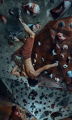 Image showing Free climber young man climbing artificial boulder indoors