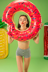 Image showing Cute girl in swimsuit posing at studio. Summer portrait caucasian teenager on green background.