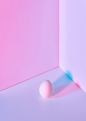 Image showing Multi-colored egg on a double pink-lilac background with a reflection of blue-pink shadows and copy space for text. Easter layout