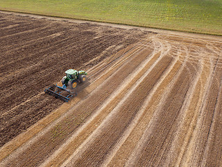 Image showing An endless agricultural field after harvesting with tractor on it . Cultivation of the soil by a tractor for sowing works.