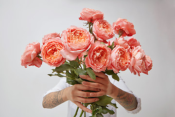 Image showing Young girl\'s hands is holding a bouquet of fresh flowers in her hands with tatoo in a color of the year 2019 Living Coral Pantone