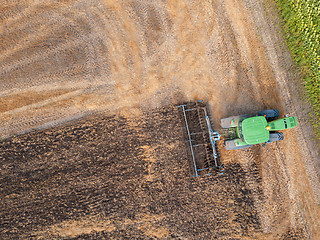 Image showing Panoramic view of the green tractor plows the field, preparing the soil for agricultural work. Top view.