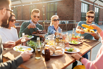 Image showing happy friends eating at barbecue party on rooftop