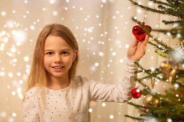 Image showing happy girl in red dress decorating christmas tree