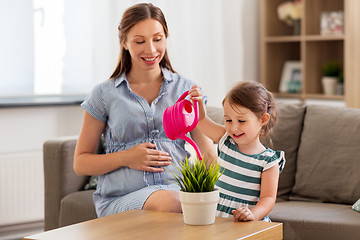 Image showing pregnant mother and daughter watering home plant