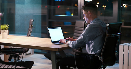 Image showing man working on laptop in dark office