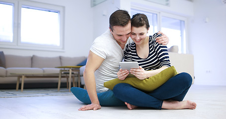 Image showing Young Couple using digital tablet on the floor