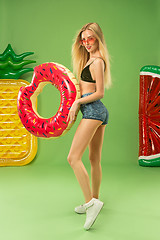 Image showing Cute girl in swimsuit posing at studio. Summer portrait caucasian teenager on green background.