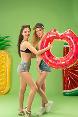 Image showing Cute girls in swimsuits posing at studio. Summer portrait caucasian teenagers on green background.